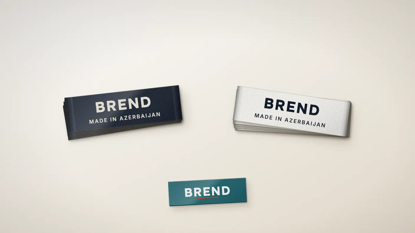 Woven vs satin labels side by side: a stack of damask woven labels next to a printed satin label